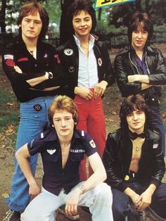 the rolling stones are posing for a photo in front of some trees and grass with their arms crossed