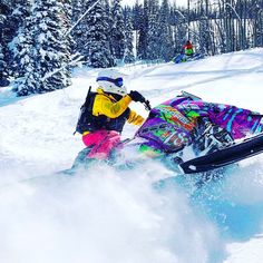 a person riding a snowboard on a snowy surface with trees in the back ground