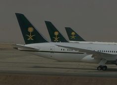 three airplanes sitting on the tarmac at an airport, one is green and white