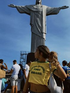 a woman is standing in front of the statue of jesus with her back turned to the camera