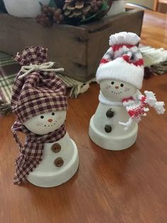 two snowmen wearing hats and scarves on top of a wooden table