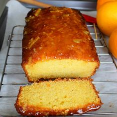 a loaf of orange pound cake sitting on top of a cooling rack next to some oranges