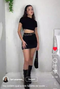 a woman standing in front of a white wall wearing short black skirt and knee high boots