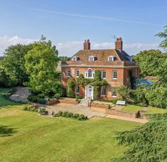 an aerial view of a large brick house surrounded by trees and grass, with a garden in the foreground