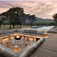 a large couch sitting on top of a wooden floor next to a swimming pool at sunset