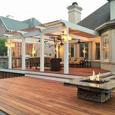 a wooden deck with a fire pit on it next to a house and patio area