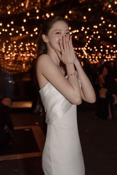 a woman in a white dress is covering her mouth