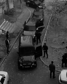 black and white photo of police officers standing near cars on the side of a road