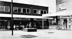 an old black and white photo of people walking in front of stores