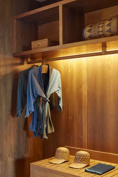 a wooden shelf with hats and shirts hanging on it's sides next to a cell phone