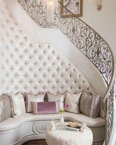 a white couch sitting under a stair case next to a table with flowers on it