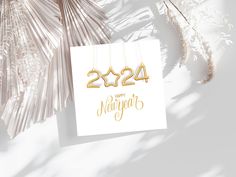 a new year's card with the numbers 2021 hanging from strings next to palm leaves