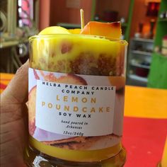 a person holding a candle in front of a jar filled with lemon poundcake soy wax