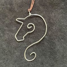 a metal horse head hanging from a cord on top of a gray carpeted floor