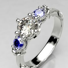 an engagement ring with three stones and blue sapphires on the sides, set in white gold