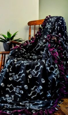 a black and purple blanket sitting on top of a wooden chair next to a potted plant