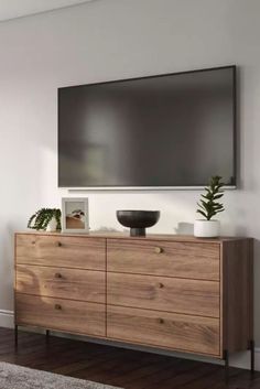 a large flat screen tv mounted to the side of a wall above a wooden dresser