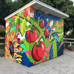 a colorfully painted outhouse sits in the middle of a parking lot next to trees