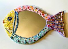 fish mirror I created and made these fish mirrors, ready to hang, on a support that I cut out of a wooden panel according to my fish drawing, I cut out a mirror, so that it fits perfectly in the center of the fish, I worked with a mixed technique, a technique that I invented for my work, it combines mosaic and painting on material, the mosaic is composed of elements such as pearls, glass beads , recycled necklaces, ceramics, glass beads... I painted with acrylic paint and 3D relief paint then I added gold glitter relief ring for a magical effect! I applied 2 coats of acrylic varnish, to enhance the colors and easy maintenance, Unique piece, signed Odile Maffone in my workshop in Drôme Provençale, handmade in France *Shipping: please give me your telephone number, it is essential for the ca Fish Mirror, Recycled Necklaces, Mirror Mosaic, Fish Drawings, Handmade Wall Art, Wall Colors, Gold Glitter, Decorative Pieces, Unique Pieces