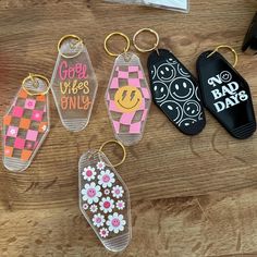 four keychains with different designs on them sitting on top of a wooden table