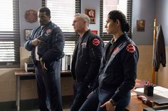 three men in uniform standing next to each other and looking at something on the table