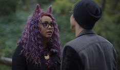 a woman with purple hair and cat ears talking to a man