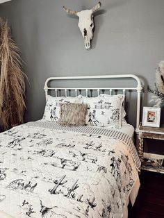 a bed with a white headboard sitting next to a night stand and vases