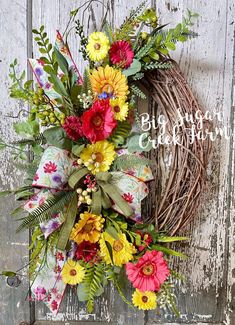 a wreath with flowers and greenery hanging on a door