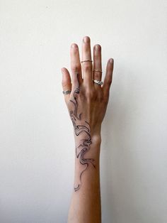 a woman's hand with a tattoo on her left arm and the other hand in the air