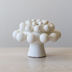 a white vase sitting on top of a wooden table filled with lots of white balls