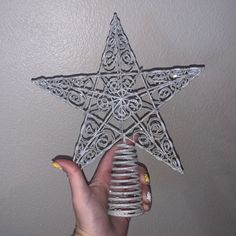 a hand holding a decorative star ornament in the shape of a spiral tube