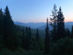 the sun is setting in the mountains with trees