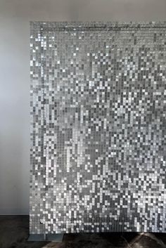 a large piece of art that is made out of silver and black squares on a white wall