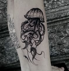 a black and white photo of an octopus tattoo on the right leg, with a jellyfish in it's tentacles