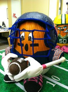 a pumpkin with a hockey helmet on it and a stuffed animal in front of it