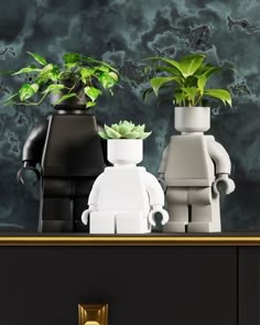 two legos are standing next to each other with plants in their pots on top of them