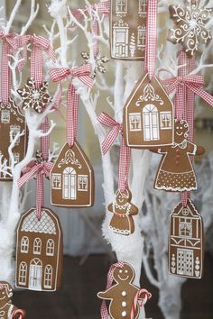 gingerbread christmas ornaments hanging from a tree in front of a house and snowflakes