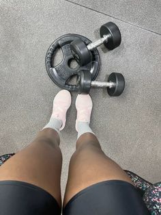 a person standing next to a pair of dumbbells on the ground with their feet up