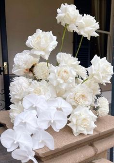 white flowers are arranged in a vase on the steps