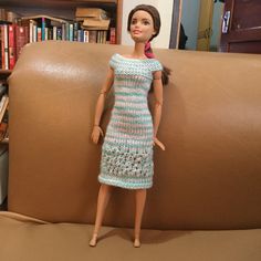 a doll is posed on a couch in front of a bookcase