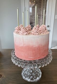 a cake with pink frosting and gold candles