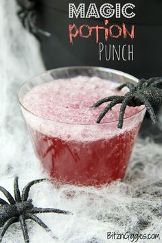 a halloween punch in a glass with spooky spider legs on the rim and text overlay that reads, magic potion punch