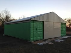 a green and white building sitting in the middle of a field