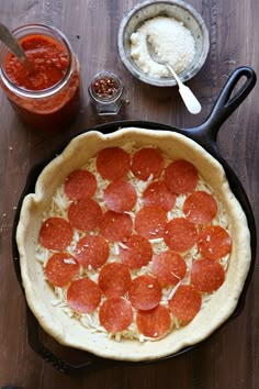 a pepperoni pizza sitting on top of a pan next to other toppings and condiments