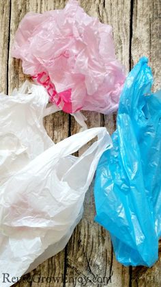 three plastic bags sitting on top of a wooden table next to each other and one bag is blue, pink, and white