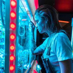 a woman standing in front of a vending machine with red lights on it's sides