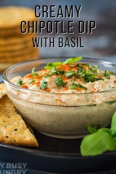 creamy chipotle dip with basil in a glass bowl and crackers on the side