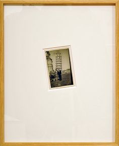 an old photo is hanging on the wall in front of a white frame with a yellow border