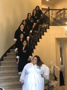 a group of women dressed in black and white posing for a photo on the stairs