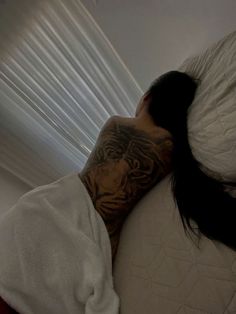 a woman laying in bed with her head on the pillow covered by a white blanket